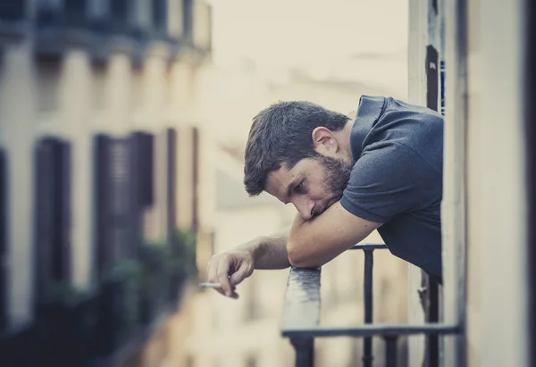 Молодой человек на балконе в депрессии страдает эмоциональным кризисом — стоковое фото