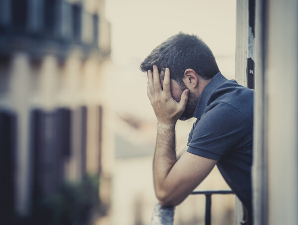  young man at balcony in depression suffering emotional crisis