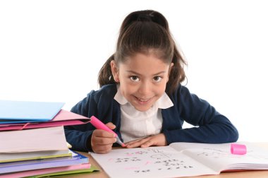 sweet happy latin child sitting on desk doing homework and smiling clipart