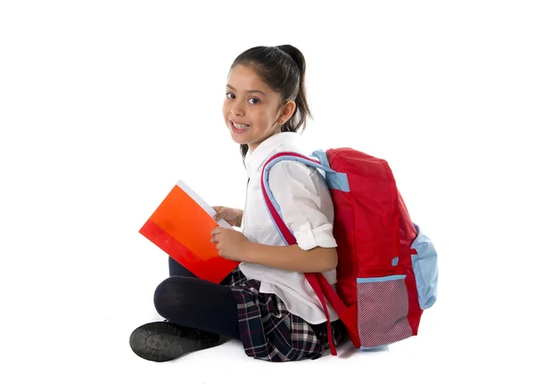 Счастливый латинский ребенок, читающий учебник или блокнот, улыбаясь сидя на полу — стоковое фото