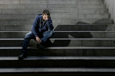 Young man lost in depression sitting on ground street concrete stairs clipart