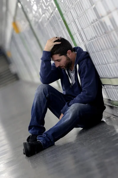 Молодой человек, потерявшийся в депрессии, сидит в тоннеле метро на улице — стоковое фото