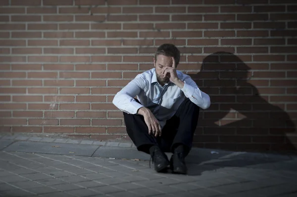 Бизнесмен, потерявший работу, впал в депрессию, сидя на углу городской улицы — стоковое фото