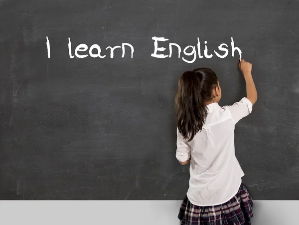 Schoolgirl writing I learn English with chalk on blackboard school — Stock Photo, Image