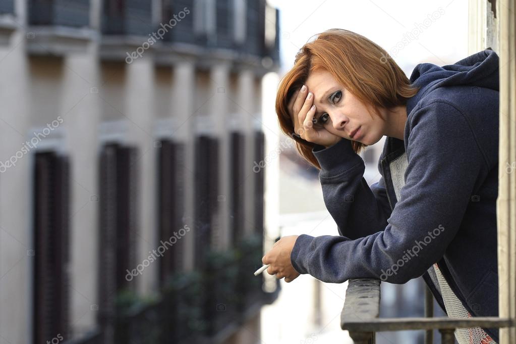 attractive woman suffering depression and stress alone in pain smoking at balcony 