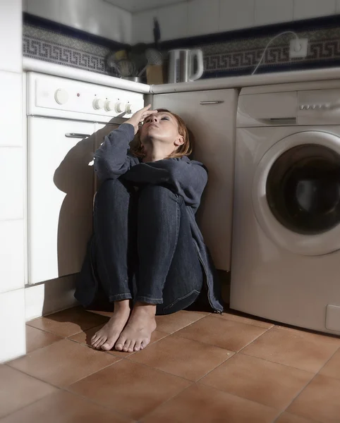 lonely and sick woman sitting on kitchen floor in stress depression and sadness