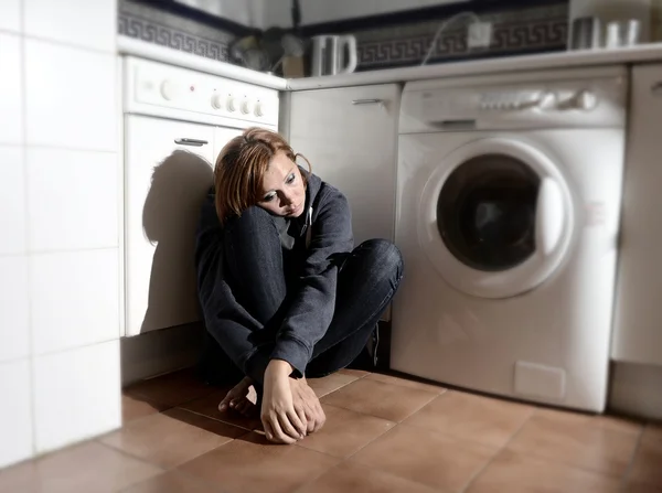 Einsame und kranke Frau sitzt in Stressdepression und Traurigkeit auf dem Küchenboden — Stockfoto