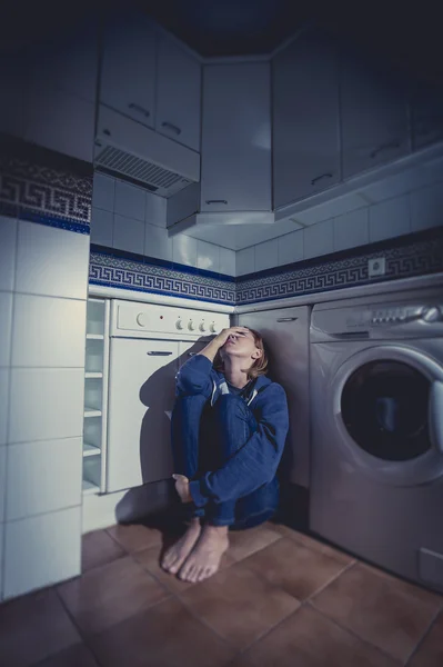 Eenzame en zieke vrouw zittend op de keukenvloer in depressie stress en verdriet — Stockfoto
