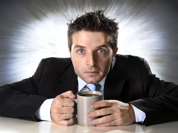 Наркоман бизнесмен держит чашку кофе тревожным и сумасшедшим от кофеиновой зависимости — стоковое фото