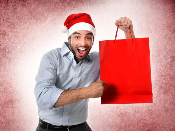 Man bär santa hatt hålla jul shopping väska leende glad — Stockfoto