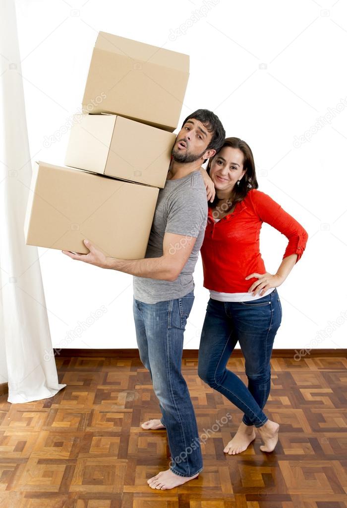 happy couple moving together in a new house carrying cardboard boxes 