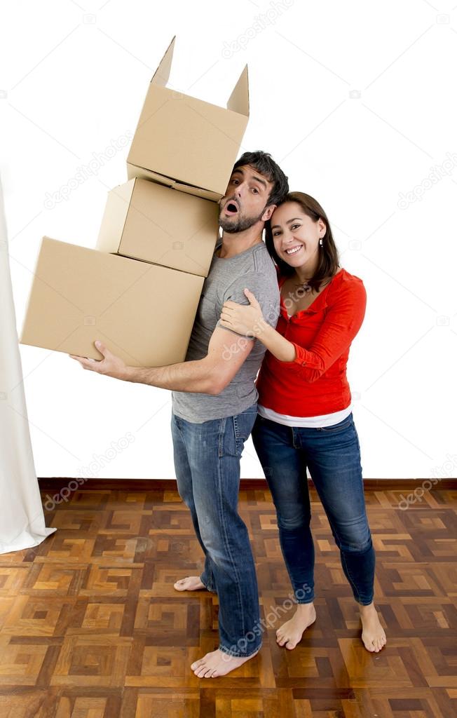 happy couple moving together in a new house carrying cardboard boxes 