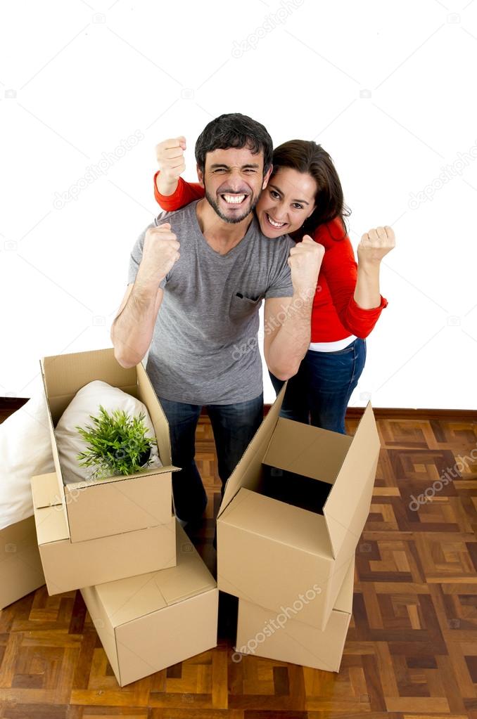 happy couple moving together in a new house unpacking cardboard boxes 