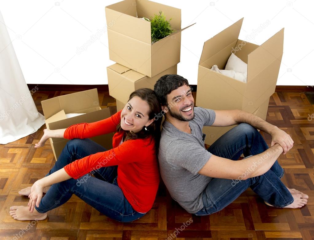 happy couple moving together in a new house unpacking cardboard boxes 