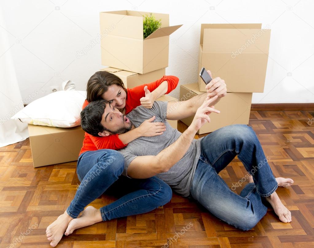 Happy couple moving together in a new house taking selfie video and pic