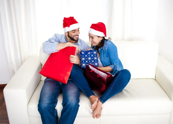 Jovem casal feliz em chapéu de Santa no Natal segurando sacos de compras com presentes — Fotografia de Stock