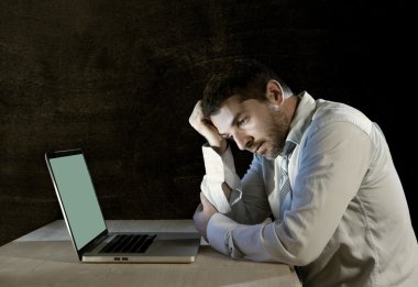 Young stressed businessman working on desk with computer laptop in frustration and depression clipart