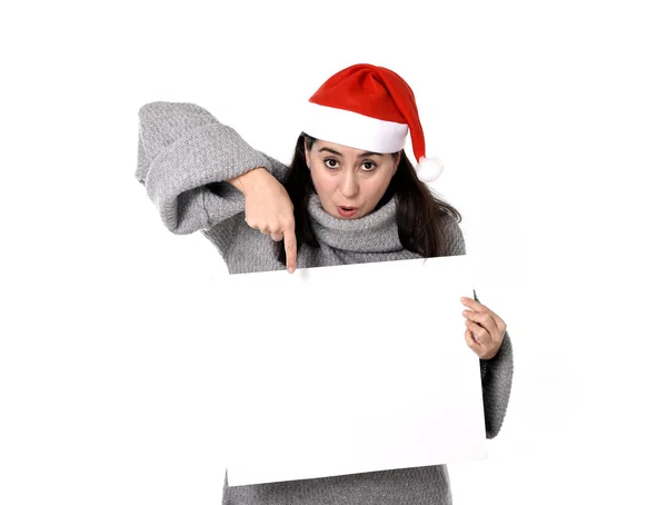 Νεαρή γλυκό Λατινική γυναίκα με καπέλο Santa Χριστούγεννα δείχνει κενός πίνακας διαφημίσεων — Φωτογραφία Αρχείου