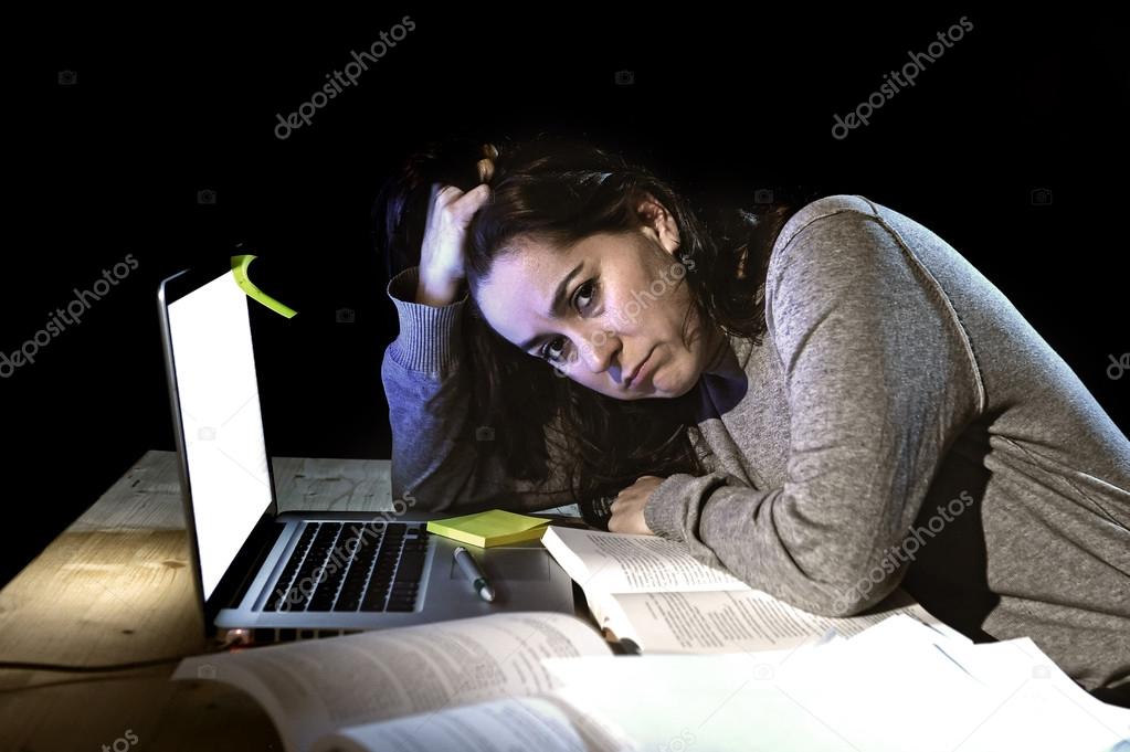 young desperate university student girl in stress for exam studying with books and computer laptop late at night