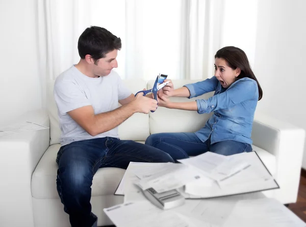 Young husband cutting credit card with scissors woman trying to stop him — Stock Photo, Image