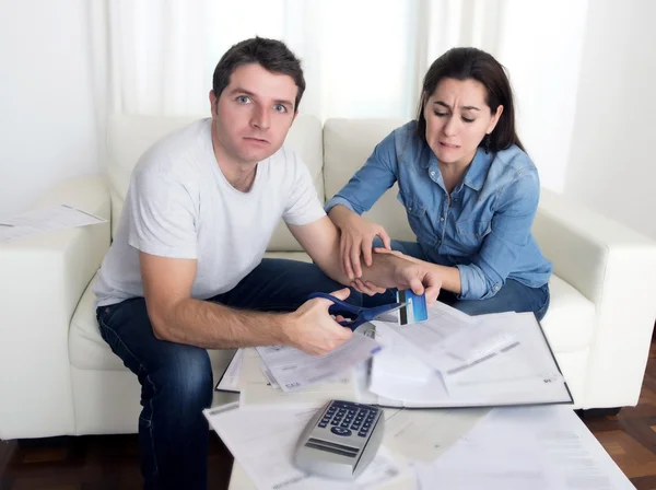 Young husband cutting credit card with scissors woman trying to stop him — Stock Photo, Image