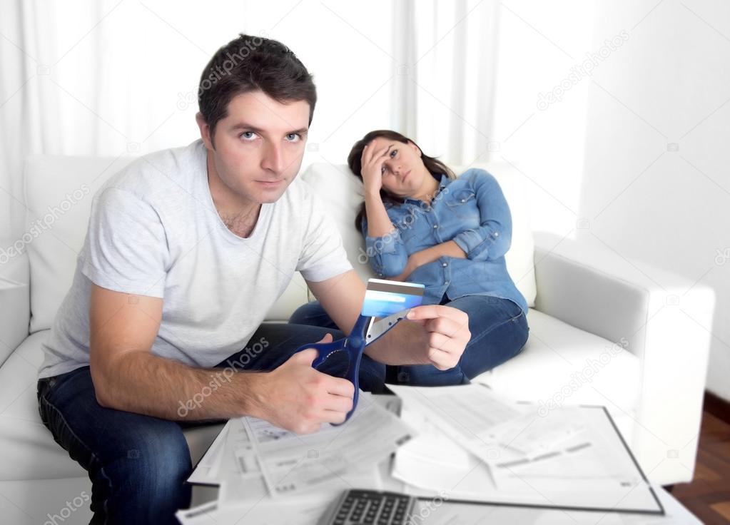 young husband cutting credit card with scissors woman depressed
