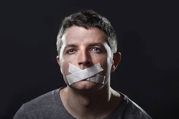 Attractive young man with mouth sealed on duct tape to prevent him from speaking — Stock Photo, Image