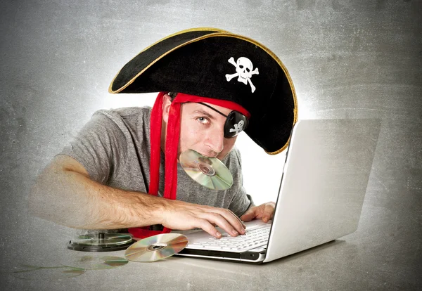 Man in pirate hat downloaden muziekbestanden en films op computer laptop — Stockfoto