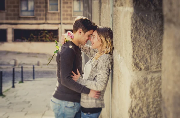 Portrait franc de beau couple européen avec rose en amour baisers sur ruelle de la rue célébrant la Saint Valentin — Photo