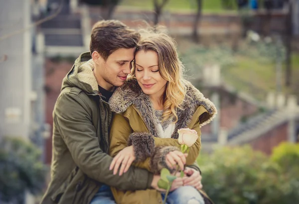 Pareja con rosa en el amor besándose en callejón celebrando San Valentín con pasión sentado en el parque de la ciudad — Foto de Stock