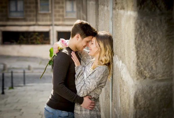 Retrato franco de hermosa pareja europea con rosa en el amor besándose en callejón celebrando el día de San Valentín —  Fotos de Stock