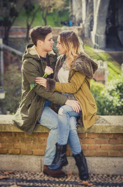 Par med rose i love kyssar på gatan alley firar alla hjärtans dag med passion sitter på stadsparken — Stockfoto