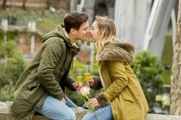 Couple in love kissing tenderly on street celebrating Valentines day or anniversary cheering in Champagne — Stock Photo, Image