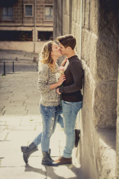 Retrato franco de hermosa pareja europea con rosa en el amor besándose en callejón celebrando el día de San Valentín —  Fotos de Stock