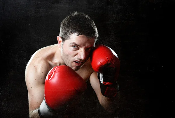 Agresivo luchador hombre boxeo enojado con guantes de combate rojos posando en posición de boxeador —  Fotos de Stock