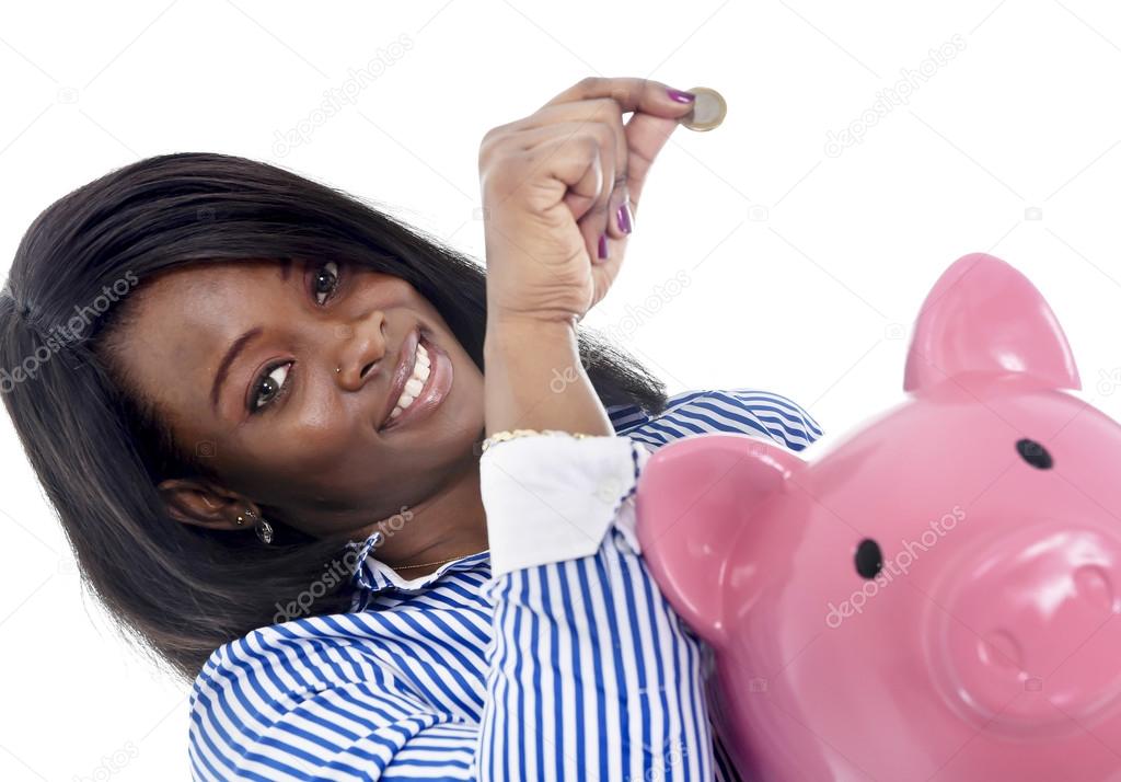 black African American business woman putting coin into oversized pink piggybank