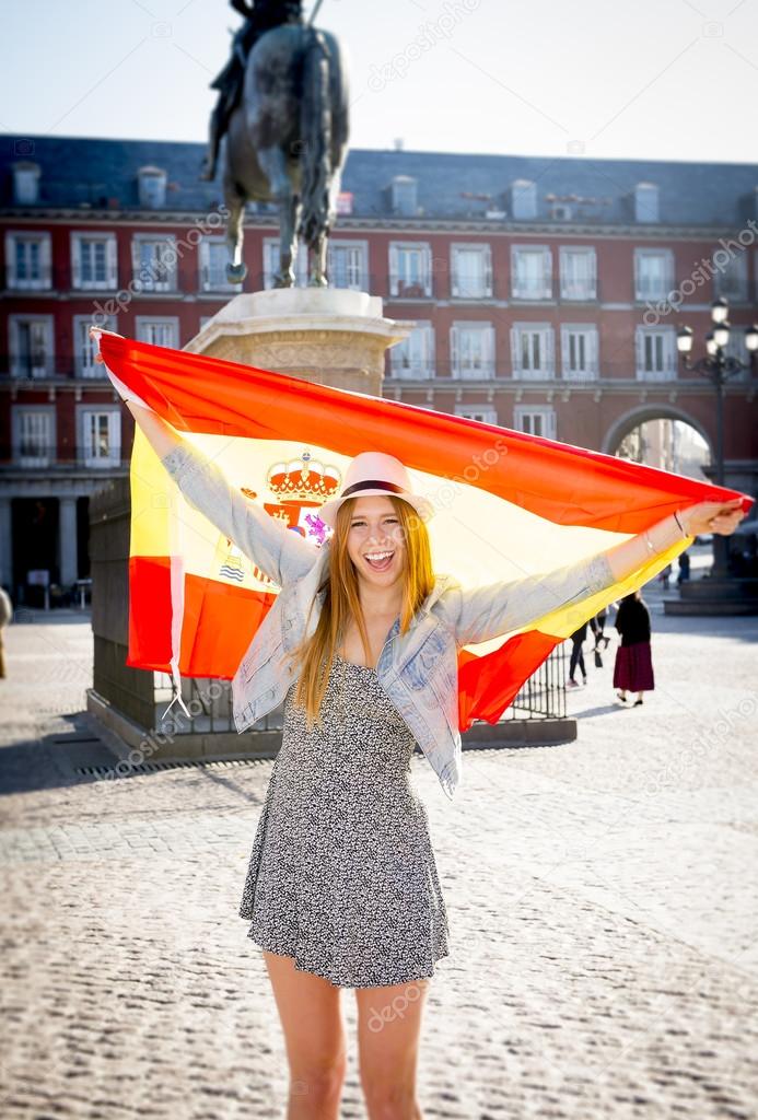 young happy attractive exchange student girl having fun in town visiting Madrid city showing Spain flag