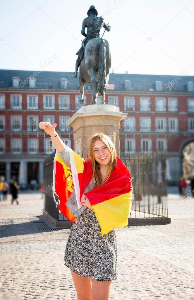 young happy attractive exchange student girl having fun in town visiting Madrid city showing Spain flag