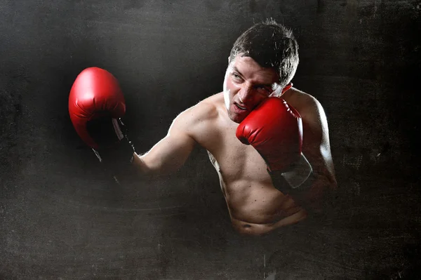 Hombre furioso entrenamiento de boxeo en el gimnasio con guantes de combate rojos lanzando golpe vicioso — Foto de Stock