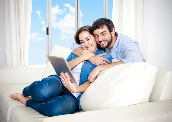 Jeune couple heureux sur le canapé à la maison profitant de l'utilisation de la tablette numérique — Photo