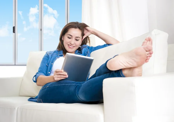 Junge glückliche Frau auf der heimischen Couch und genießt die Nutzung des digitalen Tablets — Stockfoto
