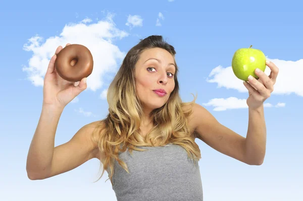 Mujer atractiva sosteniendo donut de manzana y chocolate en fruta sana versus comida chatarra dulce tentación —  Fotos de Stock