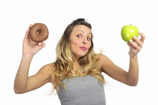 Attractive woman holding apple and chocolate donut in healthy fruit versus sweet junk food temptation — Stock Photo, Image