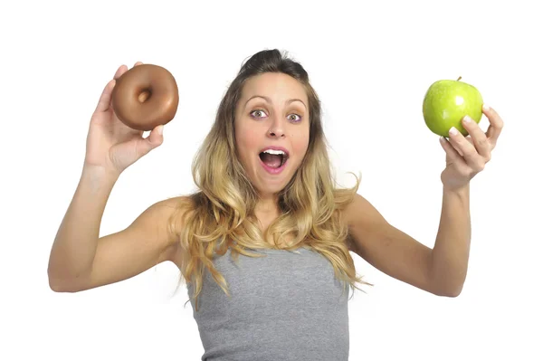 Attractive woman holding apple and chocolate donut in healthy fruit versus sweet junk food temptation — Stock Photo, Image