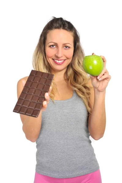 Mulher atraente segurando maçã e barra de chocolate em frutas saudáveis versus doce junk food tentação — Fotografia de Stock