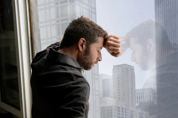 Aantrekkelijke man leunend op zakelijke district venster lijden emotionele crisis en depressie — Stockfoto