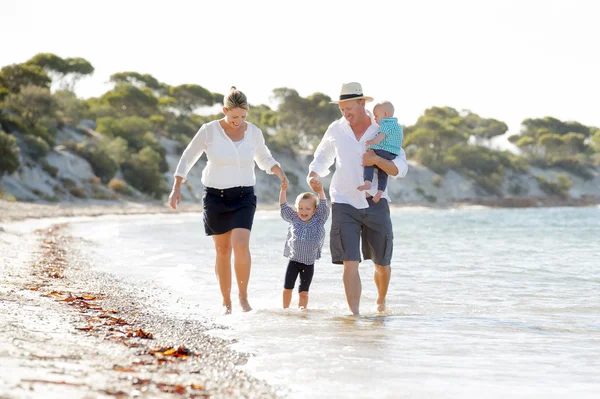 Joven feliz hermosa familia caminando juntos en la playa disfrutando de vacaciones de verano — Foto de Stock