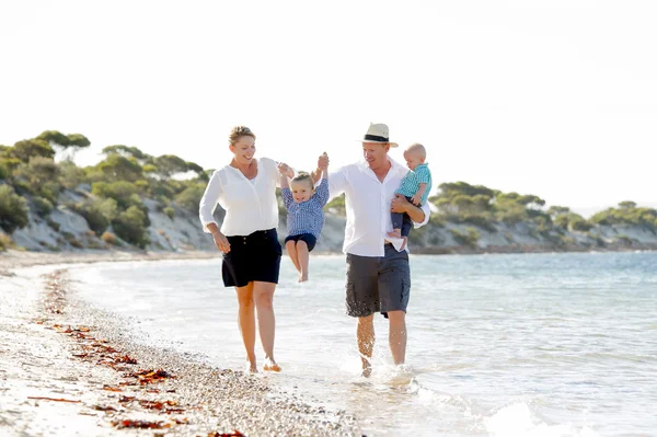 Young happy beautiful family walking together on the beach enjoying summer holidays — Stock Photo, Image