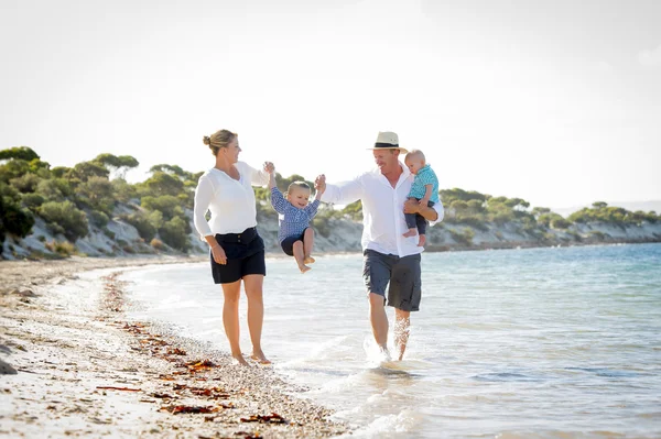 Young happy beautiful family walking together on the beach enjoying summer holidays — Stock Photo, Image