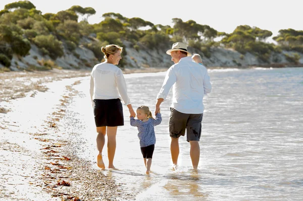 Young happy beautiful family walking together on the beach enjoying summer holidays — Stock Photo, Image